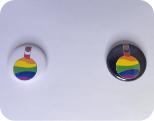 Deux badges, un noir et un blanc, avec des fioles aux couleurs du drapeau LGBT